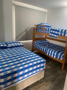 Habitación con 2 literas y sábanas azules y blancas. en Palmaire Villa 59, en San Gil
