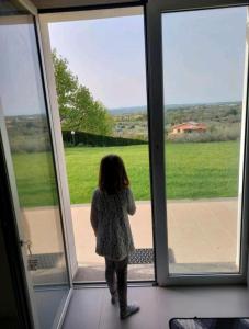 a little girl standing in front of a sliding glass door at la staccionata bianca in Viterbo