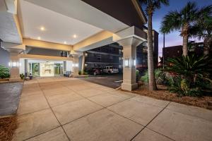 an empty sidewalk in front of a building with palm trees at Island Echos 7th Floor Condos in Fort Walton Beach