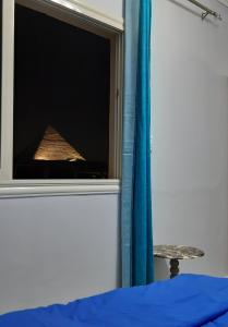 een slaapkamer met een raam met een bed en een tafel bij Aton pyramids view guest house in Caïro