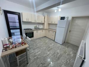 a kitchen with a table and a white refrigerator at Pensiunea Giulia in Afumaţi
