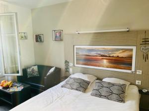1 dormitorio con 1 cama y una pintura en la pared en Appart Hôtel 3* dans une résidence de tourisme, en Le Mée-sur-Seine