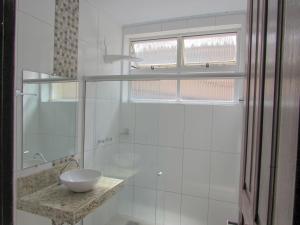 a white bathroom with a sink and a shower at San Diego Lancaster Teófilo Otoni in Teófilo Otoni