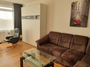 a living room with a brown couch and a glass table at LANE City Laatzen, nahe Hannover Messe in Hannover