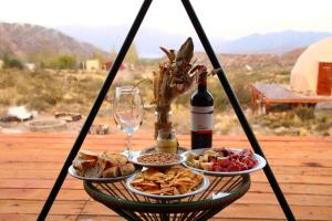 a table with two plates of food and a bottle of wine at Vista Pedra Domos in Potrerillos