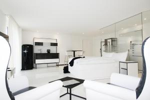 ein weißes Schlafzimmer mit einem weißen Bett und einem Sofa in der Unterkunft Residence Thessoni Home, Hotel & serviced apartments Zürich in Regensdorf