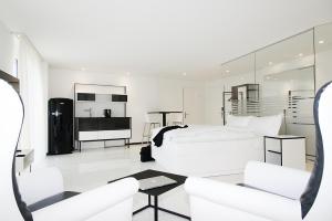 a white bedroom with a white bed and a couch at Residence Thessoni Home, Hotel & serviced apartments Zürich in Regensdorf