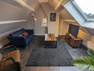 a living room with a blue couch and a tv at Knus appartement aan bosrand in Hornsterzwaag
