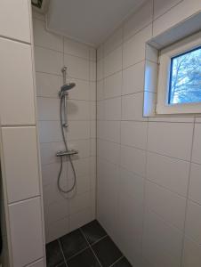 a shower in a white tiled bathroom with a window at Knus appartement aan bosrand in Hornsterzwaag