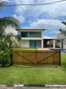 a house with a wooden fence in front of a yard at Venha se hospedar no Paraíso de Guarajuba in Camaçari