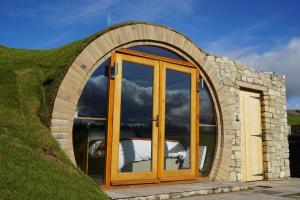 a round house with a glass door in a grassy hill at Hare's View in Rhayader
