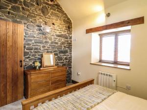 a bedroom with a stone wall and a bed and a window at Beudy Bach in Aberhafesp