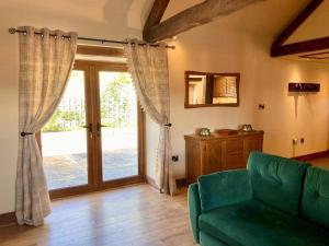 a living room with a green couch and a sliding glass door at Beudy Bach in Aberhafesp