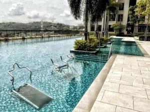 una piscina con sillas en el medio de un edificio en MsHome Suite Equnie Residence @ Taman Equnie Seri Kembangan, en Seri Kembangan