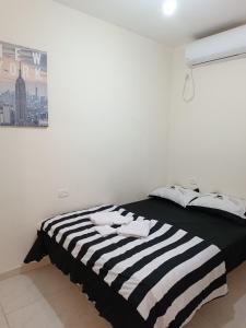een witte slaapkamer met een zwart-wit gestreept bed bij דירות אירוח לכל מטרה in Beer Sheva