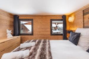a bedroom with a bed and two windows at Val Thorens - Cosy Duplex Silveralp 004 in Val Thorens
