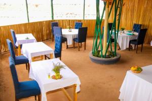 un comedor con mesas blancas y sillas azules en Amanya 2-Bed Lioness Family Tent in Amboseli, en Amboseli