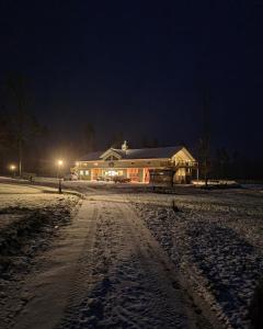 Una casa en la nieve por la noche en Mysig lägenhet med öppen planlösning på hästgård. en Ljung