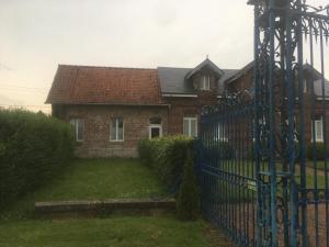 a brick house with a blue fence in front of it at Chambres d'hôtes & Gîtes du Château de Grand Rullecourt in Grand Rullecourt