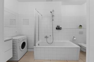 y baño blanco con bañera y lavadora. en Beautiful 80sqm Appartment in Berlin-Mitte, en Berlín