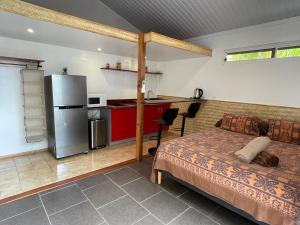 a bedroom with a bed and a kitchen with a refrigerator at Fare Ihilei in Fare