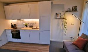a kitchen with white cabinets and a couch in a room at Staying-Inn Enschede in Enschede