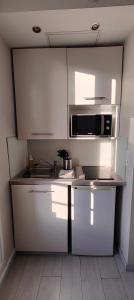 uma cozinha com armários brancos e um micro-ondas em studio-centre-Thabor-balcon-1 personne em Rennes