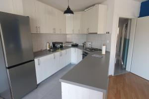 a kitchen with white cabinets and a stainless steel refrigerator at Apartment Divine Metković72m2 in Metković