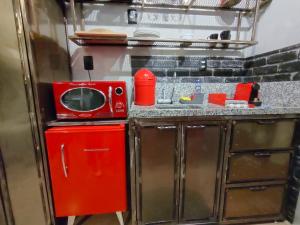 een kleine keuken met een magnetron en een rode koelkast bij Brás - O Melhor Studio 200m Estação in Sao Paulo