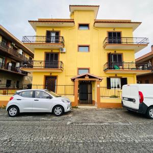 une voiture blanche garée devant un bâtiment jaune dans l'établissement Roma Tor Vergata Luxury House, à Rome