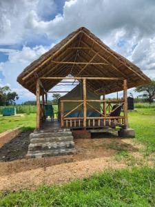 um pavilhão de madeira com um banco num campo em Ishasha Pride Lodge em Kihihi