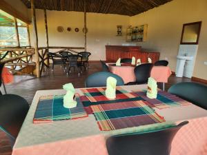 ein Esszimmer mit einem Tisch und Stühlen sowie ein Zimmer mit Tischen und einem Stuhl in der Unterkunft Ishasha Pride Lodge in Kihihi