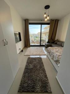 a bedroom with a bed and a living room with a window at Cozy studio in G cribs in Hurghada