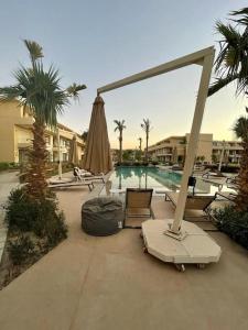 a swimming pool with chairs and an umbrella and a swimming pool at Cozy studio in G cribs in Hurghada