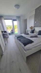 a bedroom with a large bed with a large window at Lugas Apartman in Villány