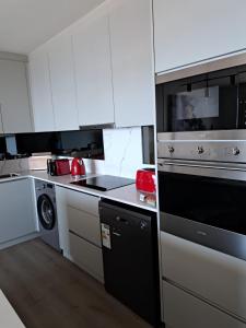 a kitchen with white cabinets and a stove top oven at The Marlo Apartment in Cape Town