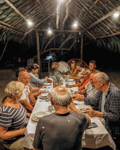 um grupo de pessoas sentadas à volta de uma mesa a comer em Kamar Raja GuestHouse em Selpele