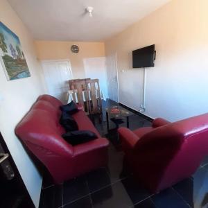 - un salon avec un canapé rouge et une chaise dans l'établissement VILLAPPART troisième étage, à Antananarivo