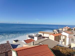 a group of houses with the ocean in the background at villa com piscina entre o mar e as montanhas in Paul do Mar