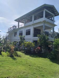 um grande edifício branco com um relvado em frente em Taylors Country Home by Taylors Traveller's Inn- The Grande Second Floor em Catarman