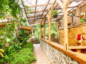 a greenhouse with plants and a stone wall at Granja Tzikin in Tzununá