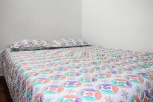 Cama con edredón colorido y almohada en Aparta Suite Torre De Prado 305, en Medellín