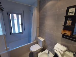 a bathroom with a white toilet and a window at Casa na onda Liberdade in Nazaré