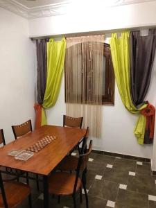 a dining room with a wooden table and yellow curtains at Villa Carimo in Quseir