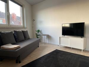 een woonkamer met een bank en een flatscreen-tv bij Tower View Apartment in Lübeck