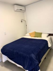 um quarto com uma cama grande e um cobertor azul em Apartamento Artístico - Garagem - Ar Condicionado - Excelente Localização em Bento Gonçalves