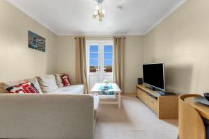 sala de estar con sofá y TV de pantalla plana en Modern 1BR flat - free parking + lift en Edimburgo