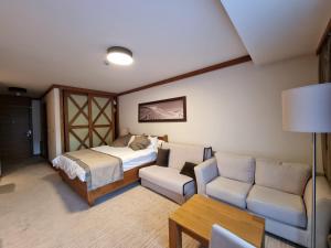 a bedroom with a bed and a couch and a table at Apartman Lukas privatni app u sklopu aparthotela Vučko in Jahorina