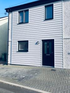 a white building with a door and two windows at Cozy & Spacious home In the heart of Snowdonia in Llanddeiniolen