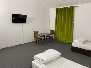 a room with two beds and a table and a television at GREEN APPLE GUEST House in Tashkent